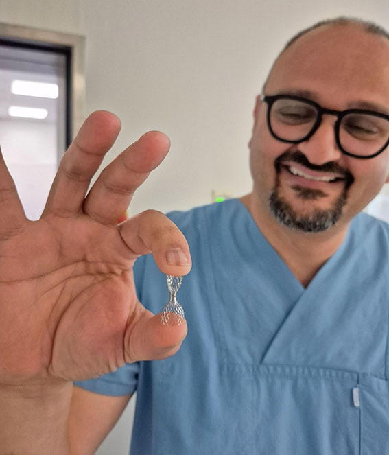 Prof. Dr. Vedat Tiyerili hält ein Muster des innovativen Implantats in Händen.
